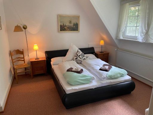 Helles Schlafzimmer mit Doppelbett , Nachttischen und Fensterblick auf die Natur.